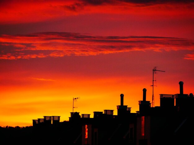 Silhouette of city against orange sky