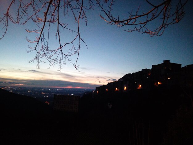 Silhouette of city against sky at sunset