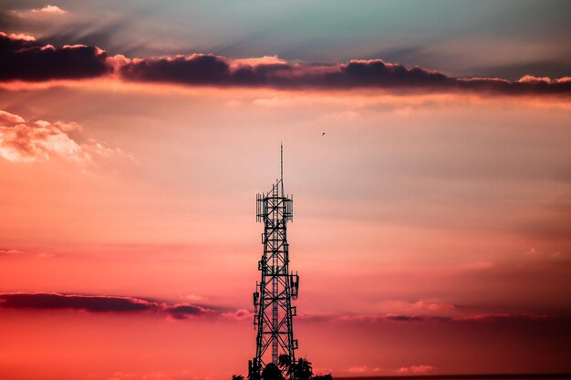 Silhouette of communications tower against sky during sunset