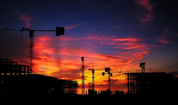 Photo silhouette construction site and abandon building with sunset background.