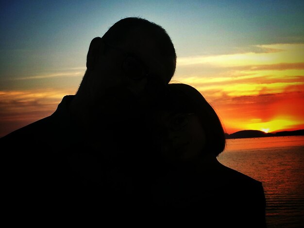 Photo silhouette couple by sea during sunset