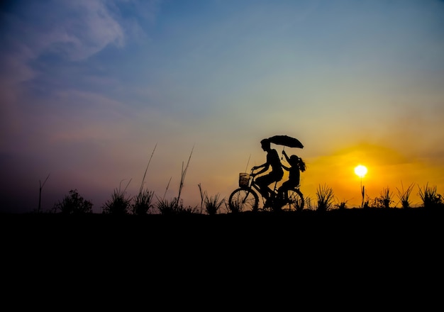 Silhouette di coppia che guida bici tempo felice tramonto