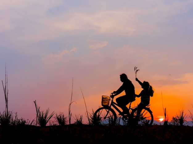 silhouette of couple driving bike happy time sunset