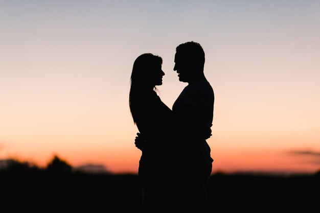 Photo silhouette of couple embracing against clear sky during sunset