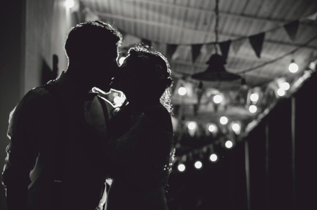 Photo silhouette couple kissing against illuminated lights