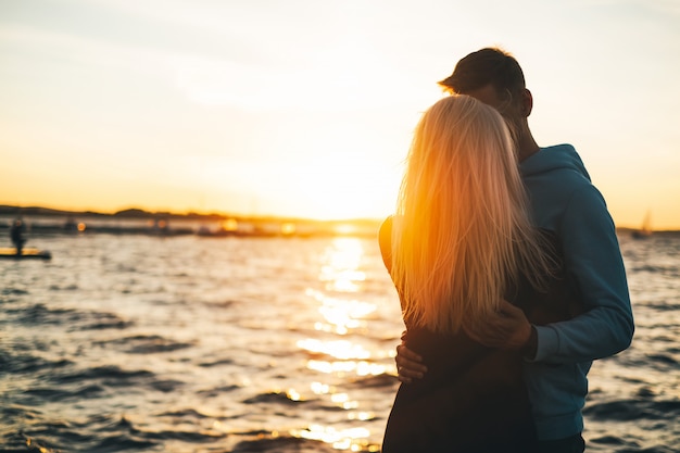 Silhouette of couple in love on the pier, sunset time