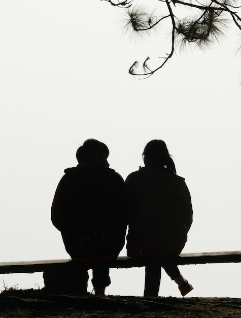 Photo silhouette couple love sitting on bench