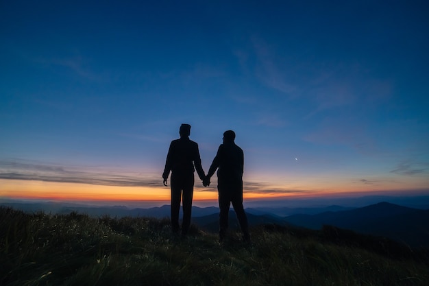 山の夕日を背景にカップルのシルエット