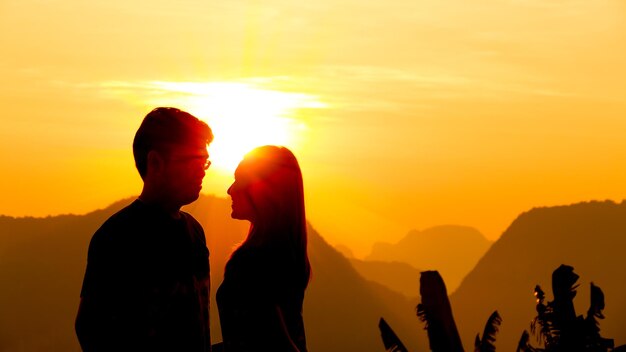 Silhouette couple romancing against sky during sunset