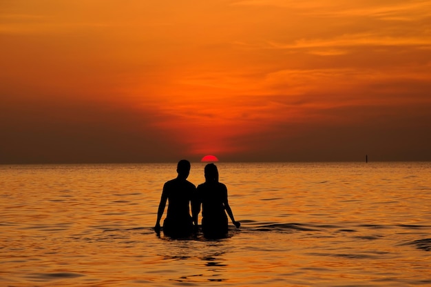 Silhouette of couple in the sea at sunset