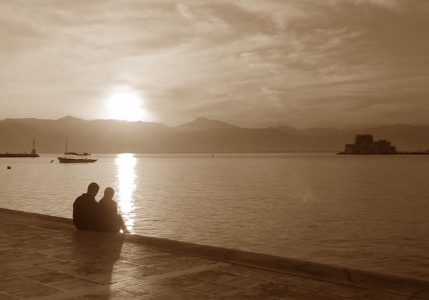 Silhouette of a couple on the seaside promenade at sunset in sepia tone