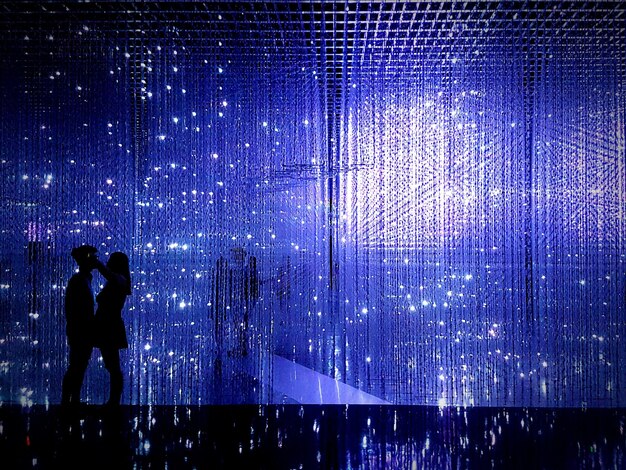 silhouette couple standing against blue lights