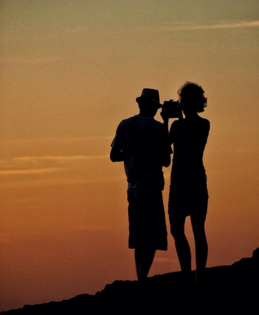 La coppia in silhouette in piedi contro il cielo durante il tramonto