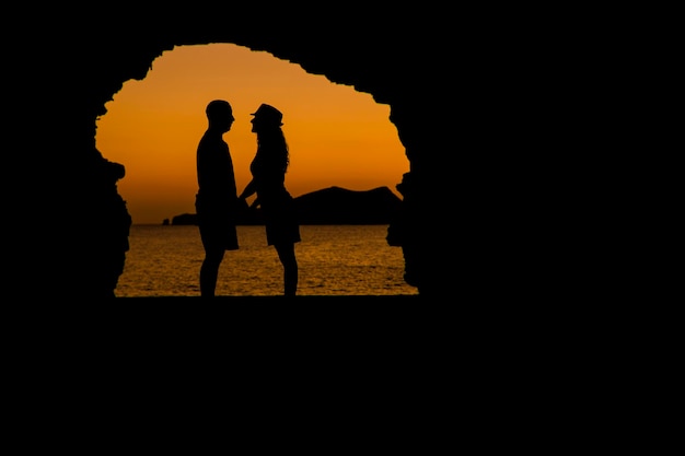 Silhouette couple standing on beach against sky during sunset