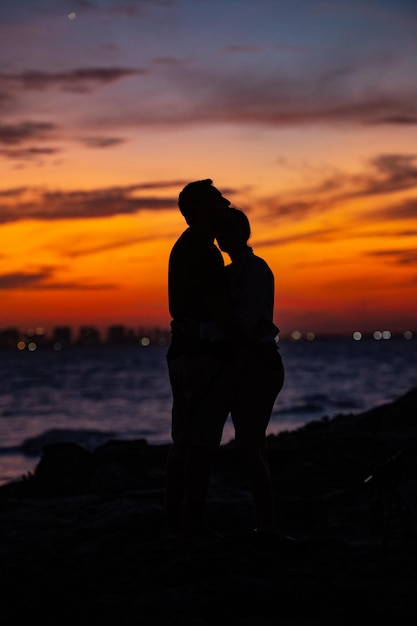 Foto silhouette di una coppia in piedi al mare contro il cielo durante il tramonto abbracciandosi esch altri