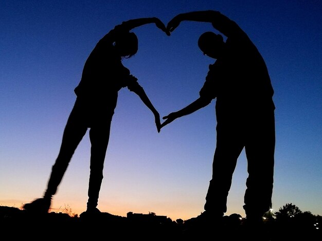 Photo silhouette couple with heart shape against sky during sunset