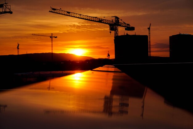 Photo silhouette crane at construction site against sky during sunset