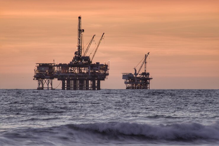 Photo silhouette crane of oil platform by sea against sky during sunset