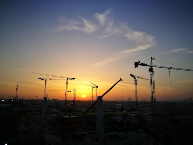 Photo silhouette cranes against sky during sunset