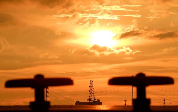 Silhouette cranes against sky during sunset