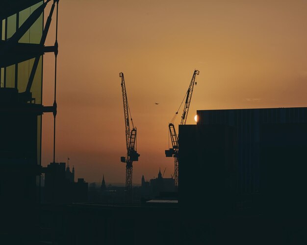 Photo silhouette cranes against sky at sunset