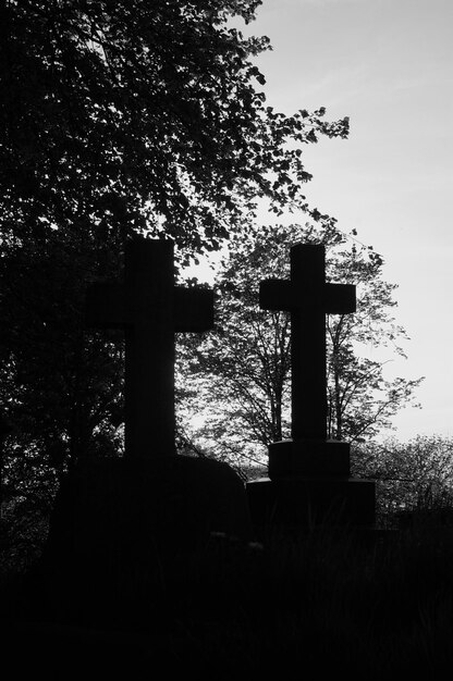 Photo silhouette of cross at cemetery against sky