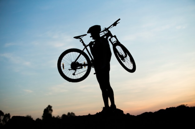 Sagoma del ciclista in sella a una bici da strada al tramonto