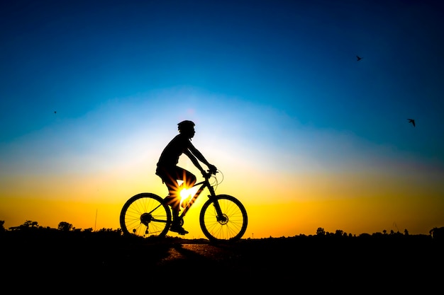 Photo silhouette of cyclist in sunset background.