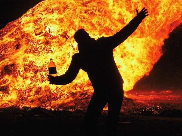 Foto silhouette di un uomo che balla contro un grande falò