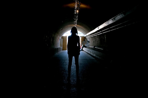 Silhouette in the dark tunnel with light at the end