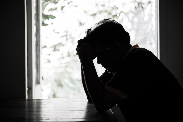 Photo silhouette depressed man sitting at table