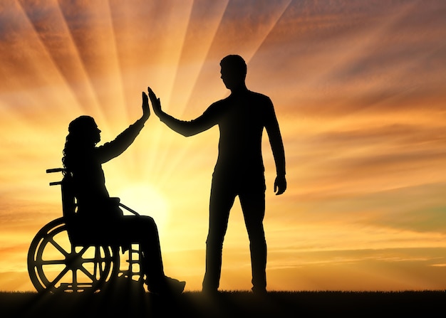 Silhouette disabled woman in a wheelchair is having fun with her boyfriend at sunset. The concept of support and assistance to people with disabilities