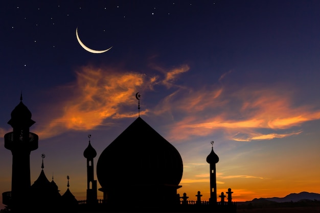 Silhouette dome mosques on dusk sky and crescent moon