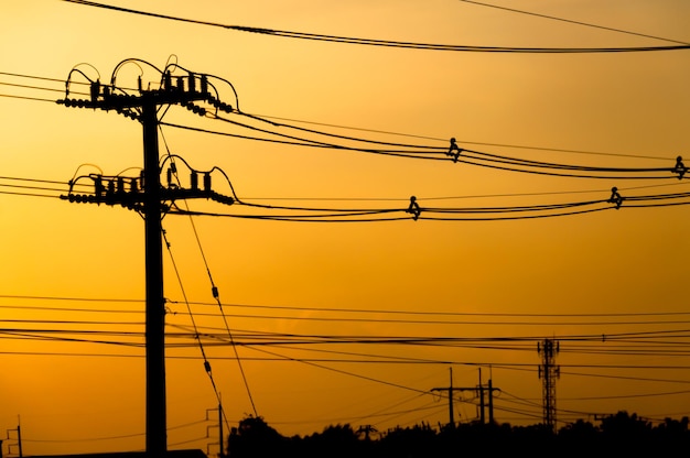 Silhouette of electric pole with cable on dramatic sunset sky horizontal frame