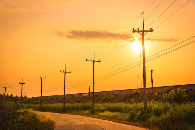 美しい夕日の背景とシルエットの電気ポスト