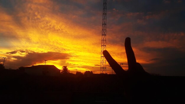 Silhouette electricity pylon against dramatic sky during sunset