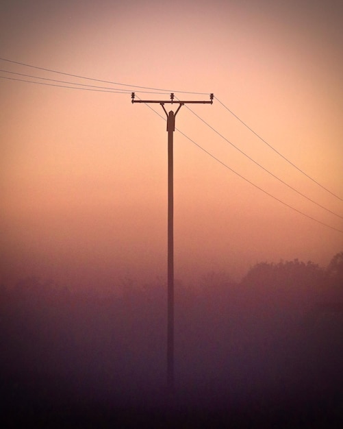 Photo silhouette electricity pylon against sky during sunrise