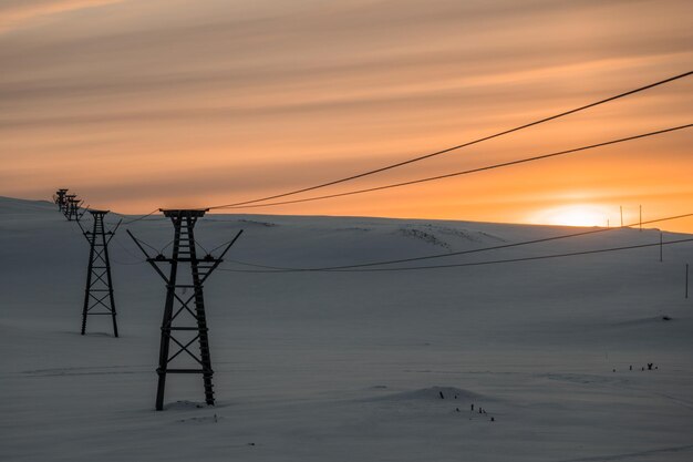 Silhouette electricity pylon against sky during sunset