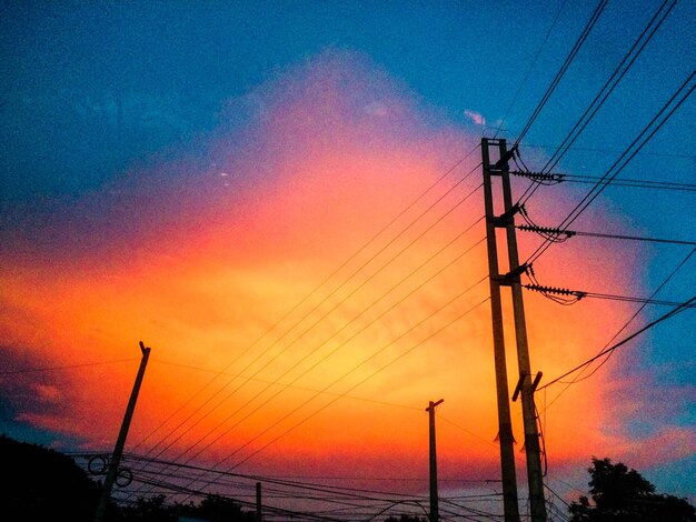 Silhouette electricity pylon by sea against romantic sky at sunset