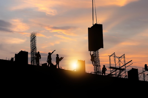 Silhouette di un ingegnere e di un lavoratore che controllano il progetto in un cantiere edile