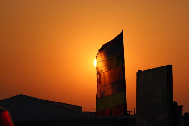 Silhouette factory against orange sky