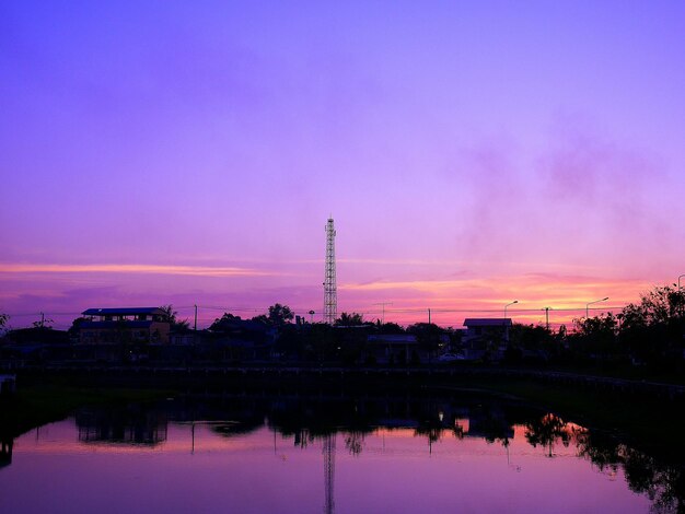 Silhouette of factory against sky at sunset