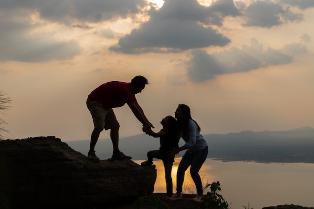 Silhouette of family on a mound at sunset. 