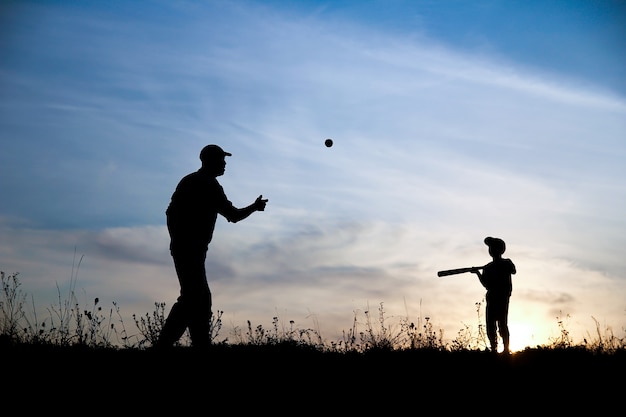 Silhouette of father and son playing baseball on nature family sport concept