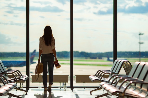 Silhouette of female airline passenger in an airport lounge waiting for flight aircraft