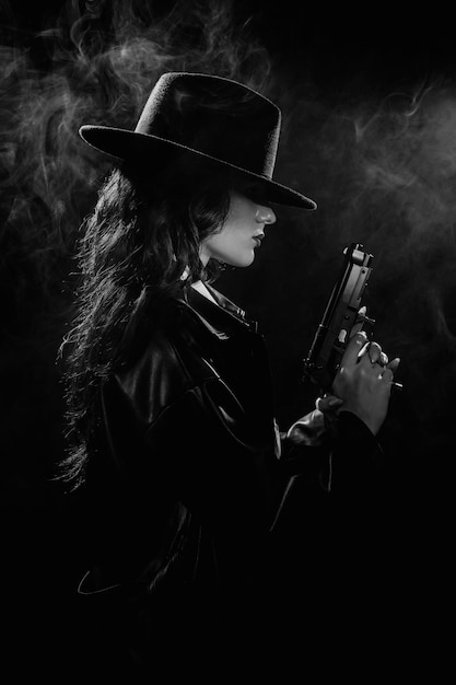 Foto silhouette di una detective in cappotto e cappello con una pistola in mano