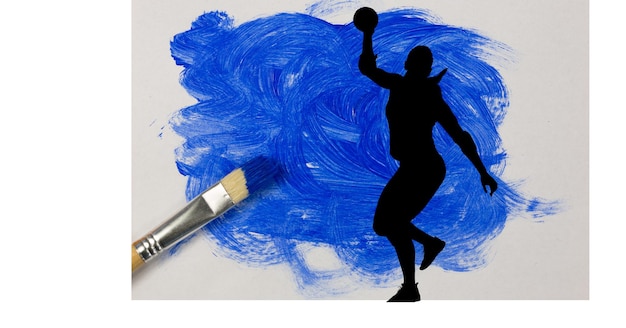 Silhouette of female handball player against blue paint stain and paint brush on white background