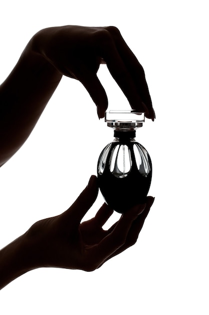 Silhouette of female hands holding a perfume bottle isolated on white background