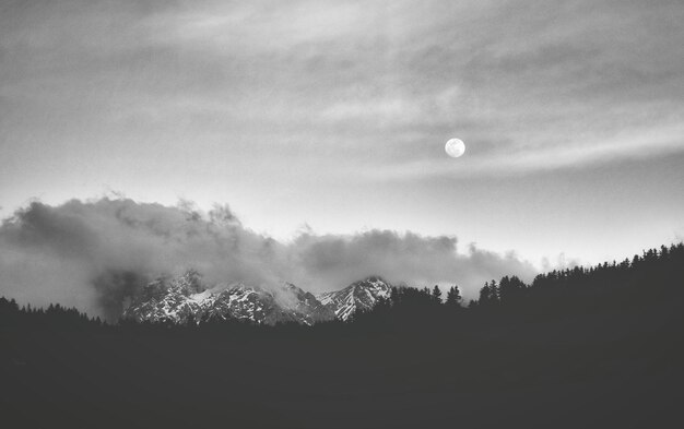 Foto campo di silhouette e montagne innevate contro il cielo