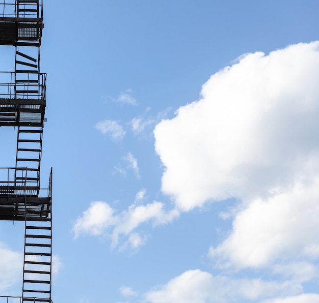 Photo silhouette of a fire escape on a highrise building against a blue sky